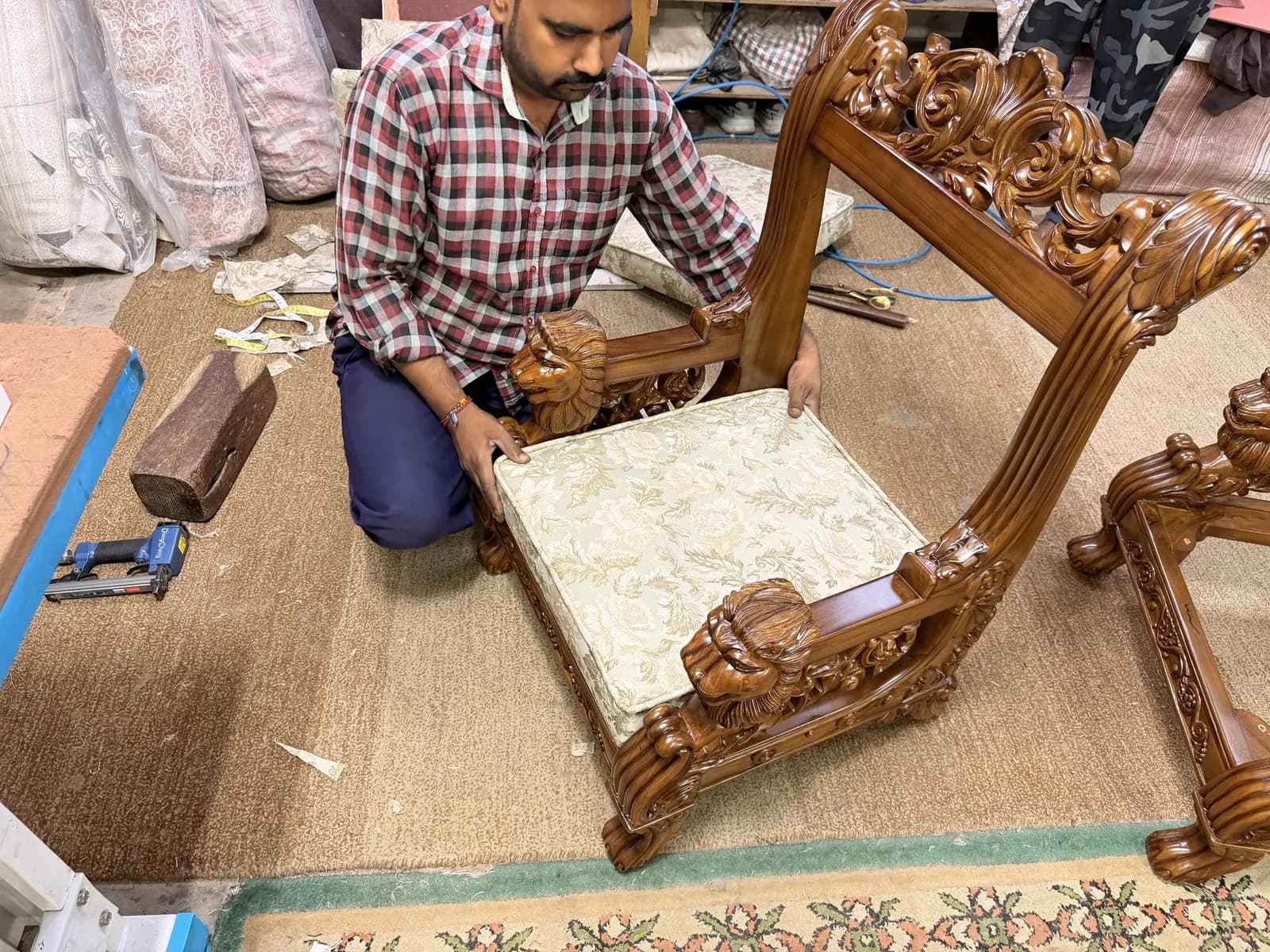 Master upholsterer hand-fitting blue and gold damask jacquard cushion to solid teak Singhasan throne